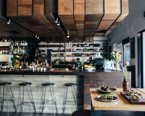 Ambiente restaurante moderno con barra, taburetes y aperitivos en mesa.